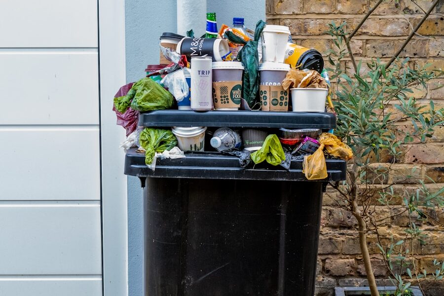 black trash bin with green leaves